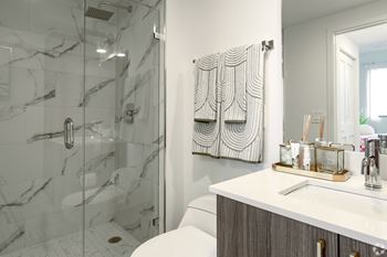 A bathroom with a marble walk-in shower and a white counter at Hollywood Heights on the Boulevard Luxury Apartments in Hollywood, FL